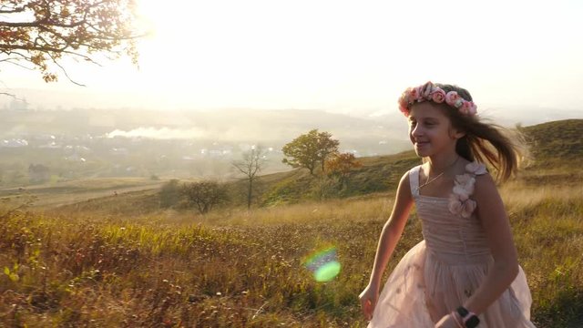 Happy cute girl running in the meadow. Amazing landscape on the background.