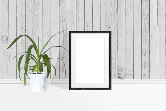 Photo frame mockup and Yucca plant in flower pot near wooden  wall