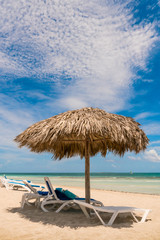 Inviting lounge chairs under tropical umbrella on the beach