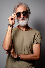 Studio portrait of handsome senior man with gray beard and sunglasses.