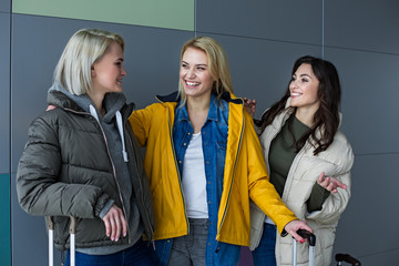 Fototapeta premium Joyful travelers sharing impressions from excursion abroad. They are standing with luggage and expressing positive emotions