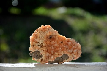 Orangener Mineralien Quarz Stein im Sonnenlicht vor grüner Natur