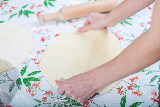 Female hands rolling out dough for homemade baking.