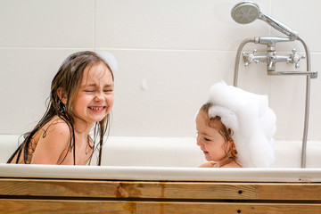 Two little sisters play in a bath. © korisbo