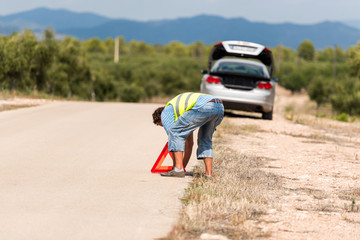 Fototapeta premium A man on the road sets an emergency sign, Tarragona, Catalunya, Spain. Copy space for text.