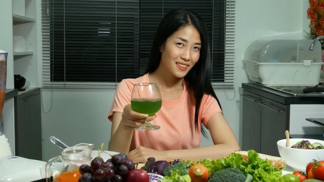 4k of young woman drinking vegetable juice in kitchen