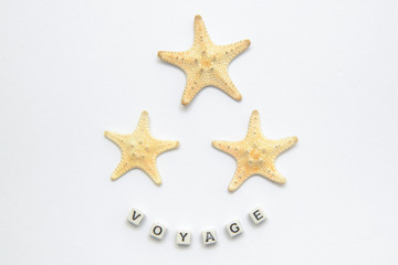 Fototapeta na wymiar Three starfish on a white background with an inscription voyage