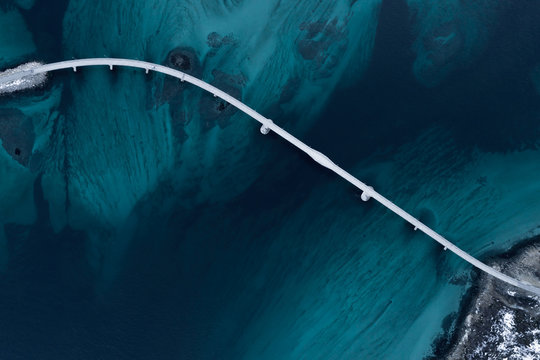 Fototapeta Aerial shot of a bridge over sea strait. Visible depth with blue and green colours near Tromso. Sommaroy, Norway