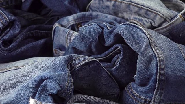 A pile of different blue jeans. Fashion things from denim as a background. HD video clip