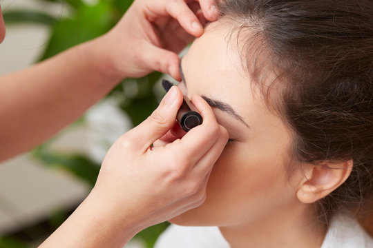professional make up artist applying mascara on woman's eyelashes