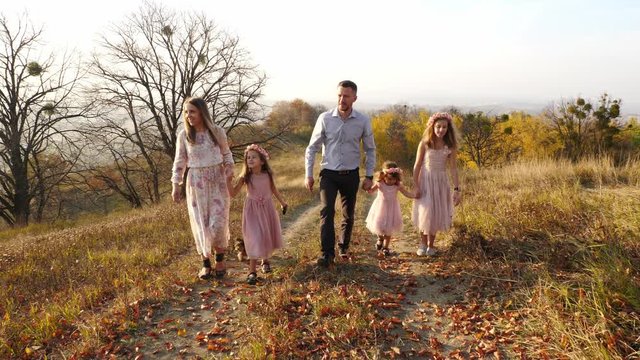 Happy young luxury dressed family walking in the autumn park with their dog