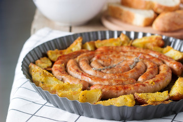 Aromatic meat sausages with potatoes, salad and wine on a wooden background. Selective focus.