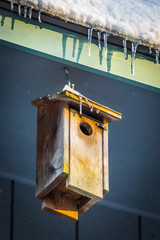Small birdhouse on the roof under icicles