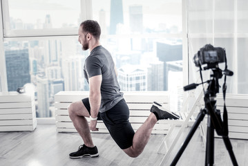 Another circuit. Ambitious professional male blogger doing exercise while using training for it and...