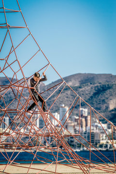 Little boy climbing on the rope at playground in Benidorm beach