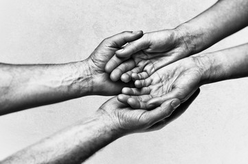 Man's hands holding female palms on scratched background. Black and white image.