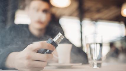 Using electronic cigarette to smoke in public places.Smoke restriction,smoking ban.Using vaping device with flavoured liquid.E-juice vaping new technology.Give up tobacco.Smoking habit,nicotine addict