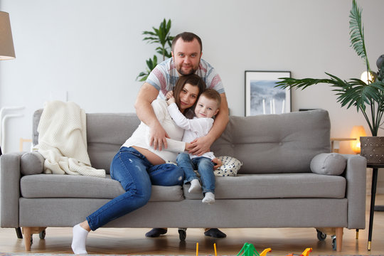 Picture of cuddling family with son on gray sofa