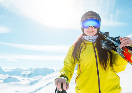 Photo of sports girl wearing helmet, a mask with skis on her shoulder