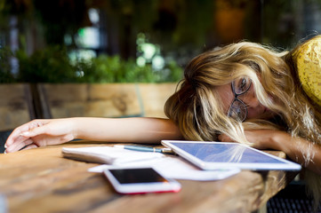 Young pretty woman tired of work lying on table in front of laptop and taking a break