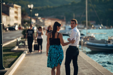 Young couple walking along the coastal lane in sunset.Man turning to see another woman,seeing ex...