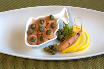 Rolls salmon with capers. With lemon and shrimp and a green accent - stalk dill.