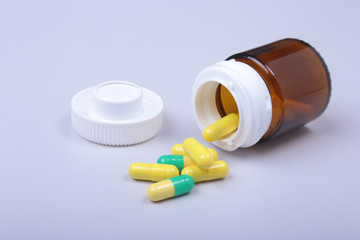 Colorful medical pills and capsules on white table with space for text.
