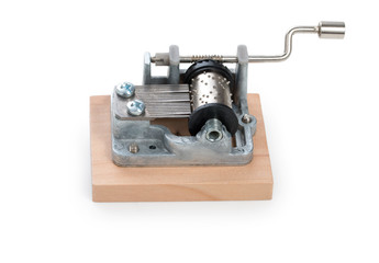 Vintage mechanical music box on a little wooden plank, isolated on white background.