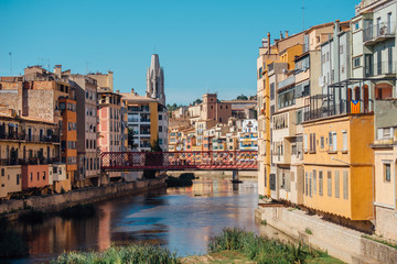 Fototapeta na wymiar Colorful yellow and orange houses and bridge Pont de Sant Agusti reflected in water river Onyar, in Girona, Catalonia, Spain.
