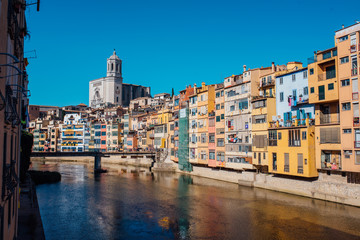 Colorful yellow and orange houses and bridge Pont de Sant Agusti reflected in water river Onyar, in Girona, Catalonia, Spain.