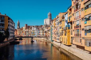 Colorful yellow and orange houses and bridge Pont de Sant Agusti reflected in water river Onyar, in Girona, Catalonia, Spain.