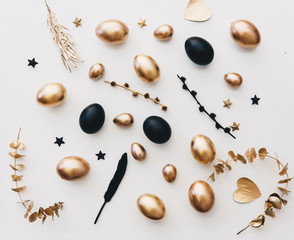 Flat lay composition with Easter eggs. Gold and black eggs over white background