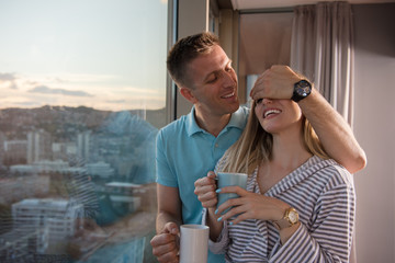 Obraz na płótnie Canvas young couple enjoying evening coffee by the window