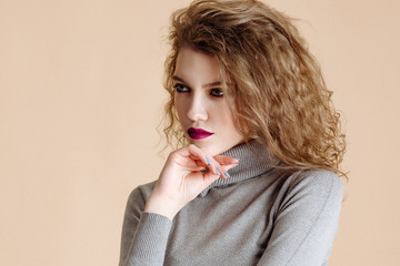 Body language and emotion. Portrait close up on a yellow background in studio. The young girl the model with curly hair looking away holding hand under chin, building plans, thinking about something