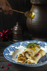 Traditional russian pancakes on blue patterned plate with fresh honey.