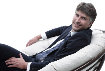 side view. Businessman sitting in comfortable armchair looking at camera