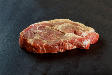 Fresh and raw meat. Whole piece of red meat ready to cook on the grill or BBQ . Background black blackboard