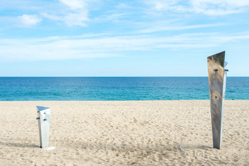 Fototapeta na wymiar deux petites douches de tailles différente sur une plage avec la méditerranéenne en fond