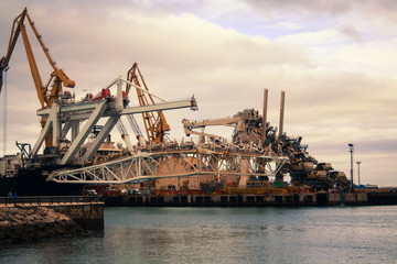 Fototapeta na wymiar Cargo cranes in the dock of the industrial port.Spain, Cadiz, February 2018.