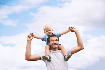 Father and son with raised arms up against the sky.