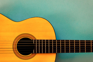 Acoustic classic guitar on blue background. Simple musical instrument with copy space.
