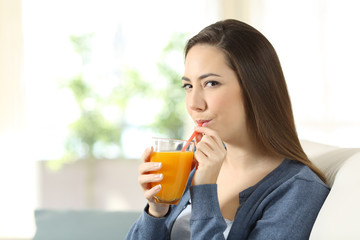 Woman drinking orange juice with a straw