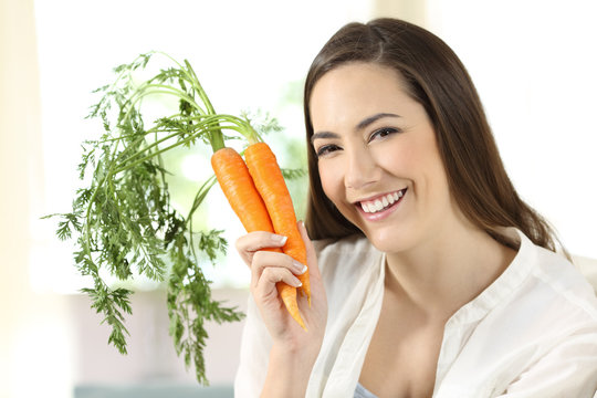 Girl showing a bundle of carrots looking at camera
