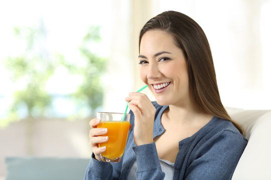 Pretty woman drinking orange juice looking at camera