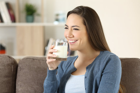 Woman holding a glass of milk on a couch