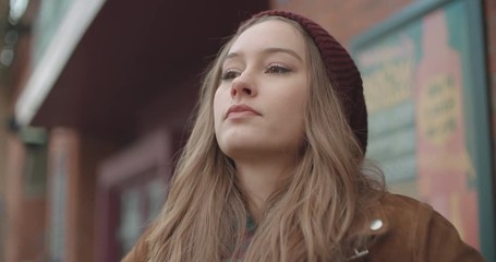 Beautiful sad anxious woman standing in a city street.