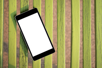 Mobile smart phone with blank screen on green wood. Technology and lifestyle concept.