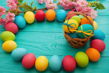 Colorful Easter Eggs and basket on blue wooden table background. Top view and copy space. Food Egg, flowers. Fun holiday
