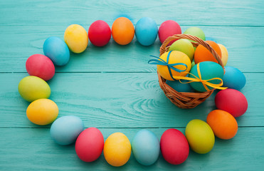 Colorful Easter Eggs and basket on blue wooden table background. Top view and copy space. Food Egg. Fun holiday