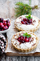 Delicious  tarts with cream and fresh cranberry on wooden table. Christmas dessert.